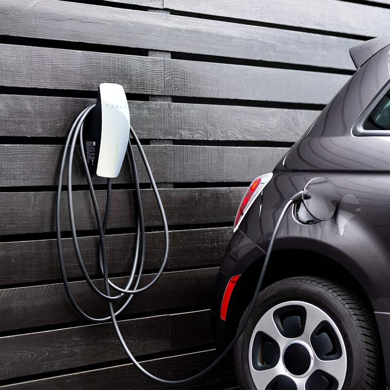 A sleek EV charger installed on a wall, connected to an electric vehicle for EV Home Charging.
