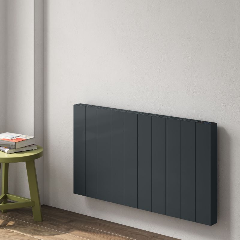 Anthracite Electric Radiators mounted on a wall beside a green stool with books.