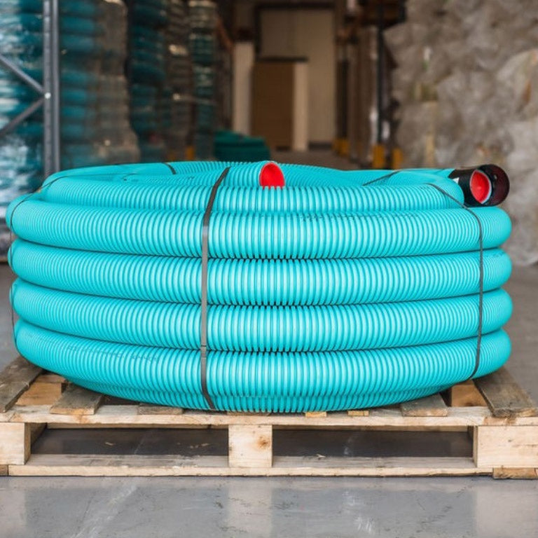 A large coiled turquoise corrugated semi-rigid ducting coil on a wooden pallet in a warehouse setting.