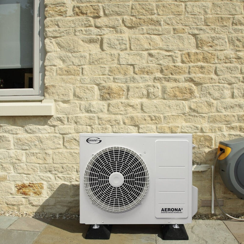 Grant Aerona3 10kW Heat Pump installed outside on a stone wall for efficient heating and hot water.