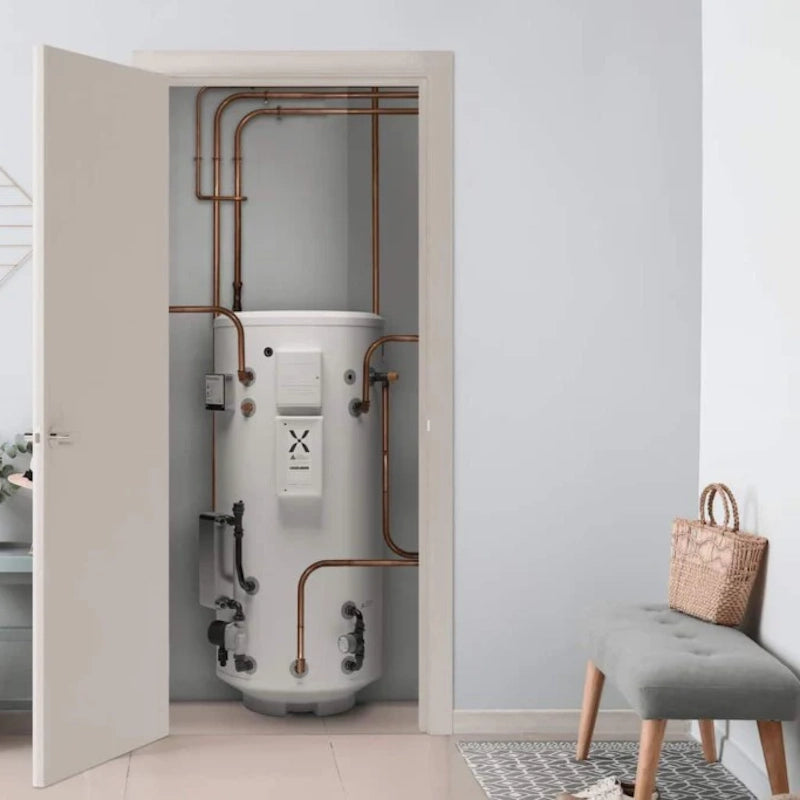 Mixergy White cylindrical water heater with copper pipes in a room with a gray wall and a chair.
