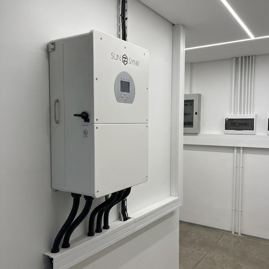 Sunsynk solar inverter mounted on a white wall in a modern commercial building.