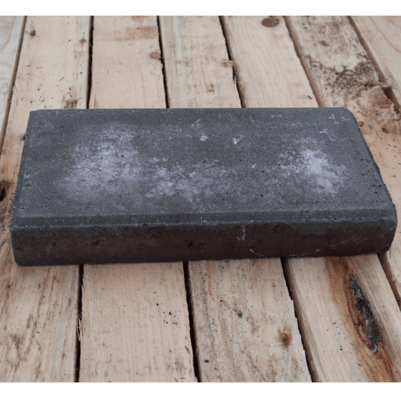 Rectangular dark gray stone block on a wooden surface